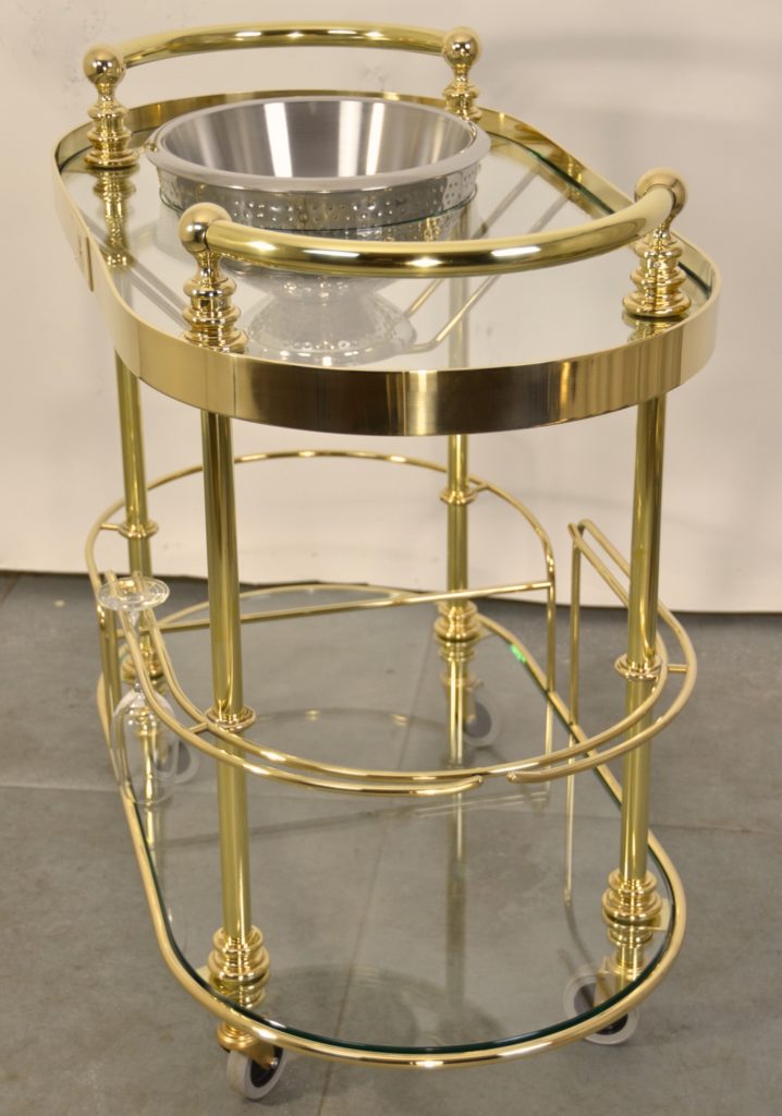 A custom made polished brass champagne trolley with glass shelves and a double-skinned stainless steel ice bowl.