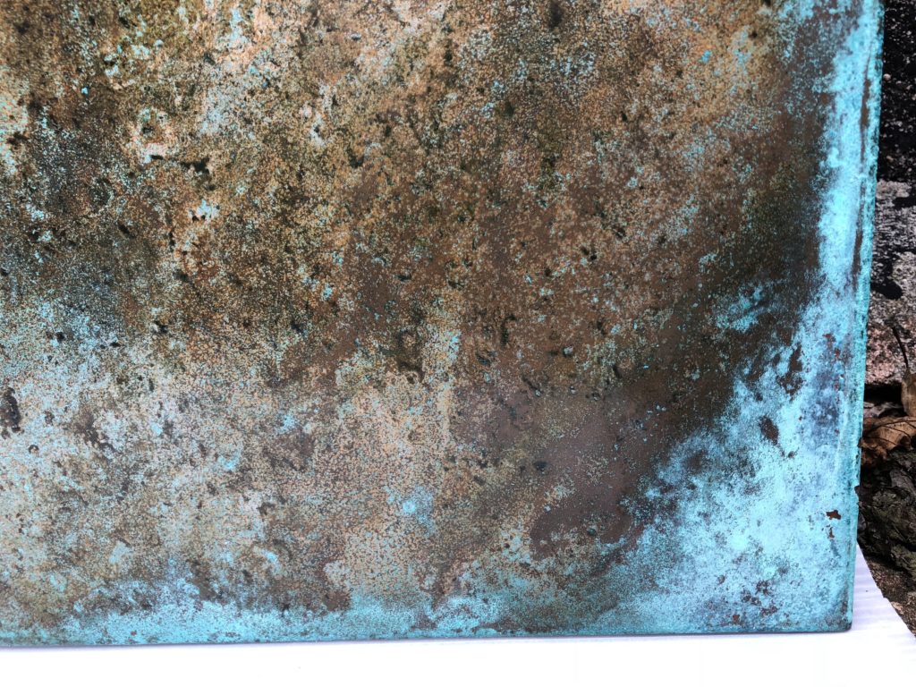 Close-up of patinated copper panels with a mix of brown, green, and blue hues