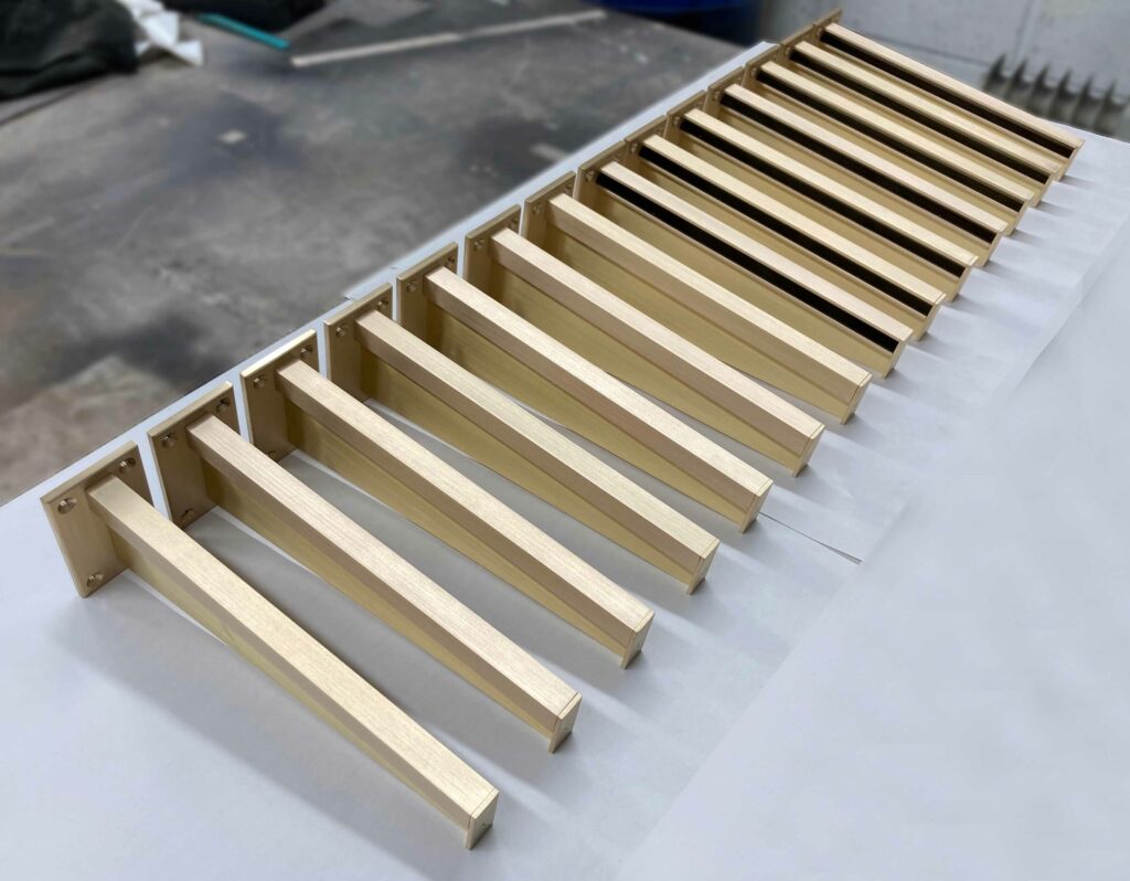 A wooden structure with a row of evenly spaced, parallel beams supported by vertical pillars on a workshop floor. The beams are light-colored and appear to be part of a construction or assembly project.