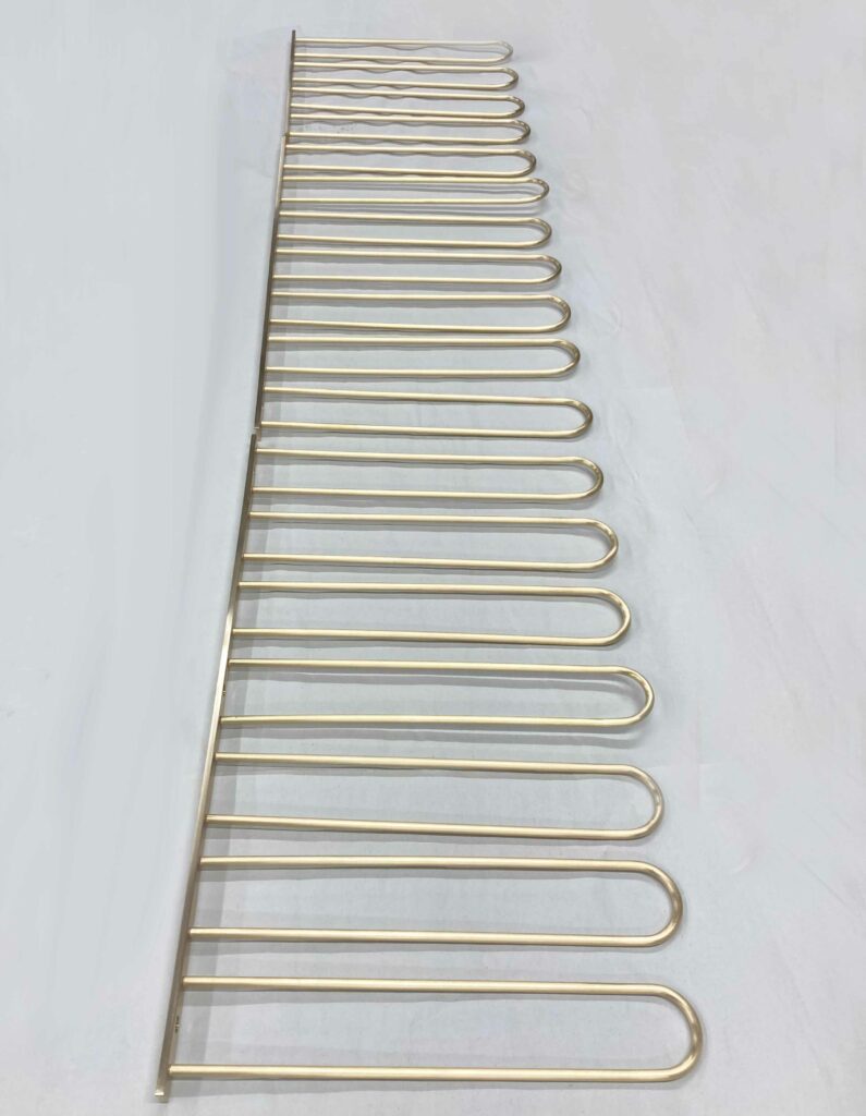 A metal rod with multiple evenly spaced, U-shaped hooks attached vertically, resembling a hanger or rail system, laid flat on a white surface.