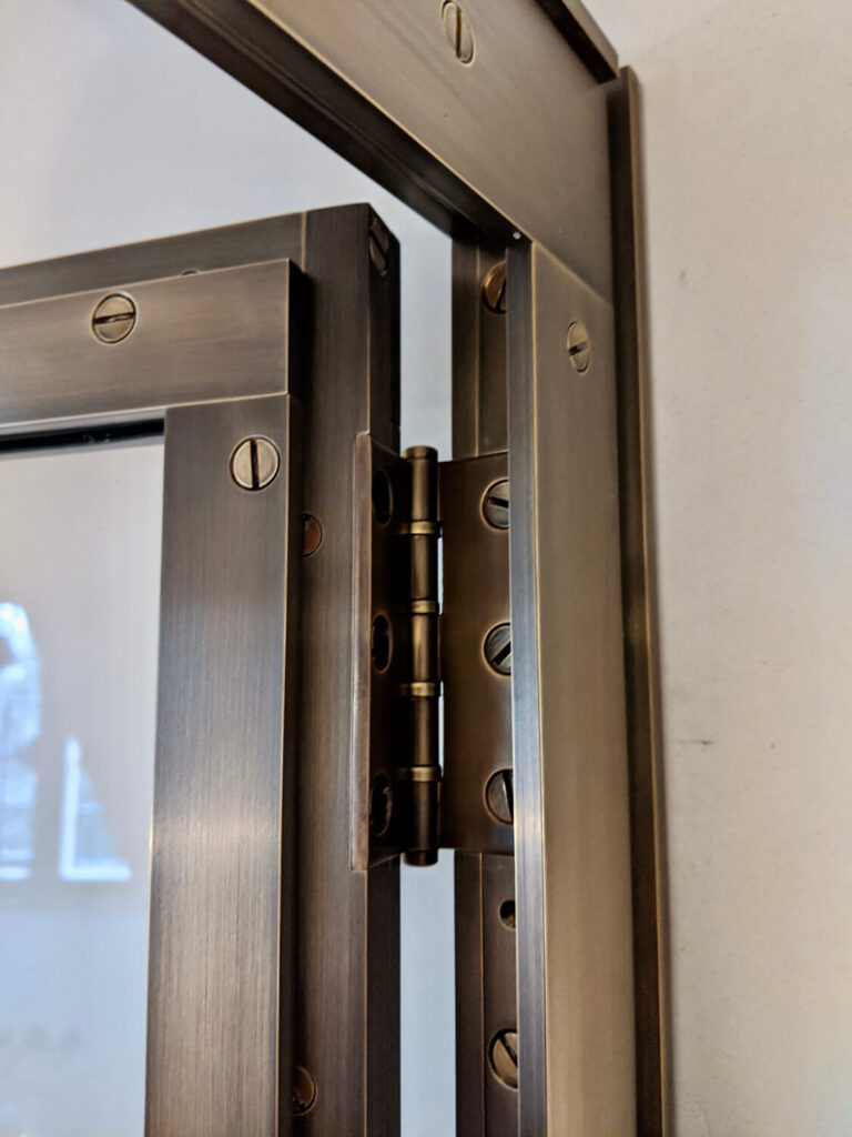 A custom hinge on a modern brass shower enclosure