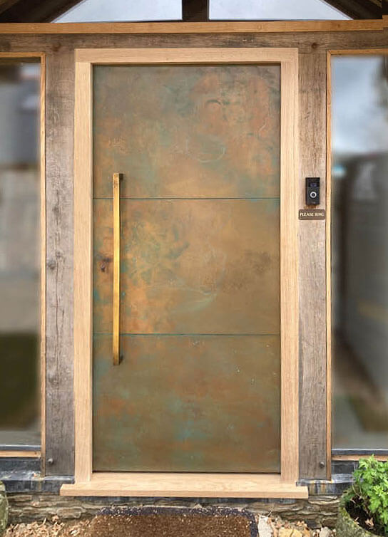 A sturdy, industrial-style metal door made of copper with a sleek wooden frame.