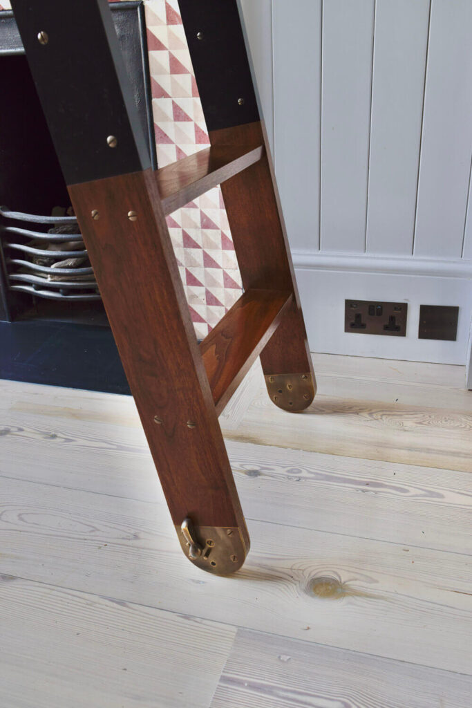 A wooden walnut library ladder with brass fittings.